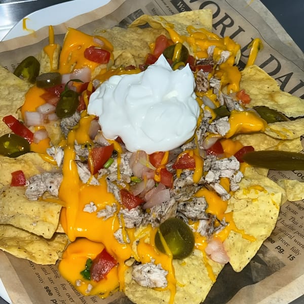Chicken nachos with melted cheese, diced tomatoes, onions, jalapeños, and a dollop of sour cream.